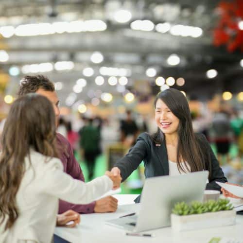 Business professionals shaking hands at a trade show stand during an event interaction